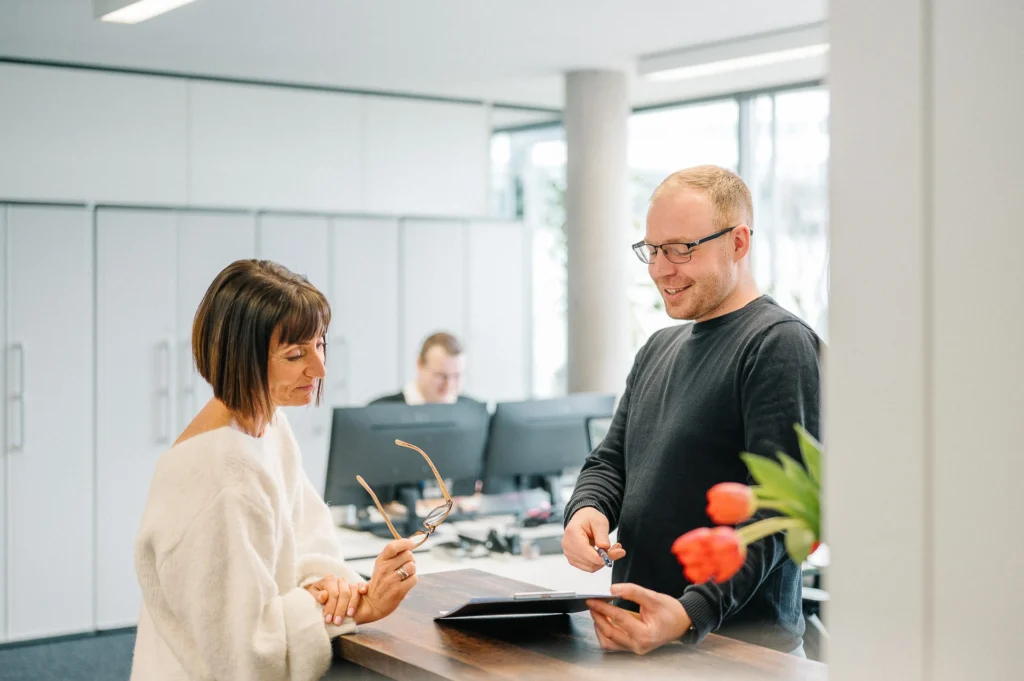 Mitarbeiterin und Mitarbeiter an der Empfangstheke der MBS GmbH im Gespräch