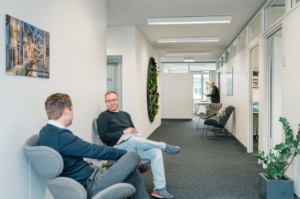 Moderne Wartezone im Eingangsbereich der MBS GmbH Freiburg mit zwei Personen im Gespräch
